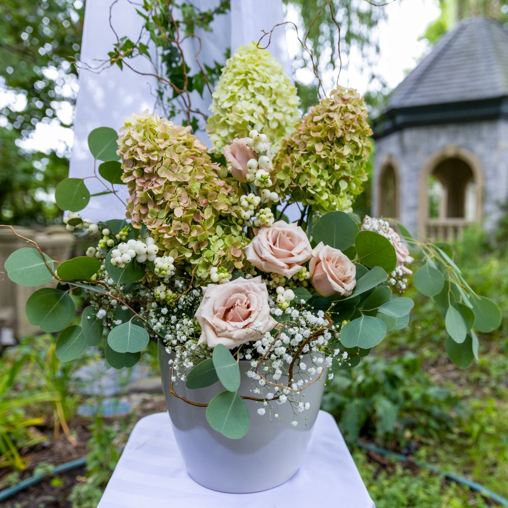 Jardinière florale mariage avec roses roses, hydrangea, gypsophile
et eucalyptus, décoration romantique style bohème