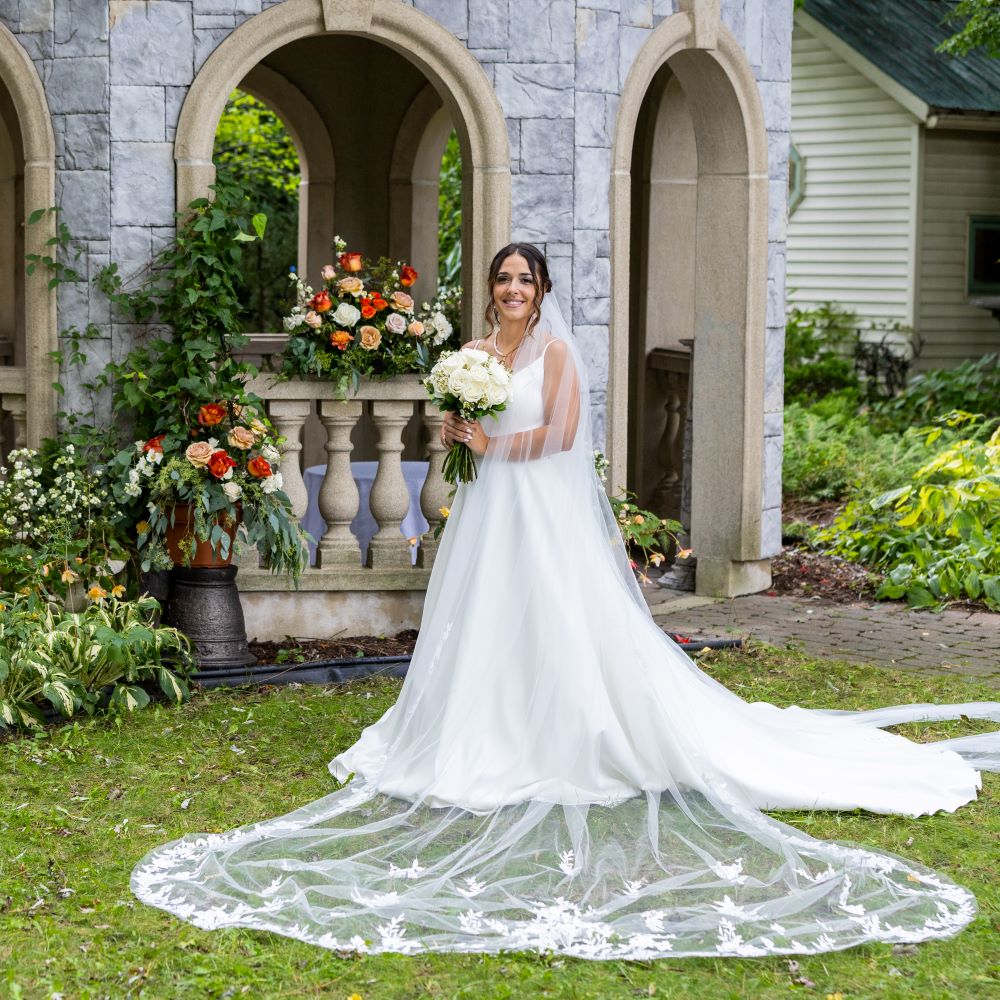 La mariée debout de face avec le voile de la robe pour un mariage chic-classique blanc