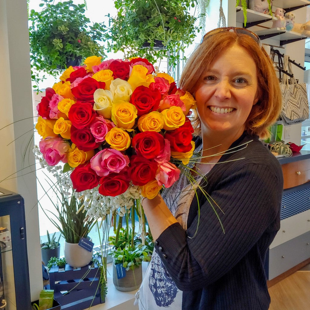 Nadia qui tient un bouquet de roses pour une livraison par le fleuriste st-basile